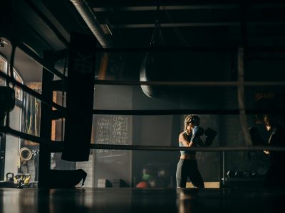 Focused female boxers sparring during a training session in a dimly lit gym.